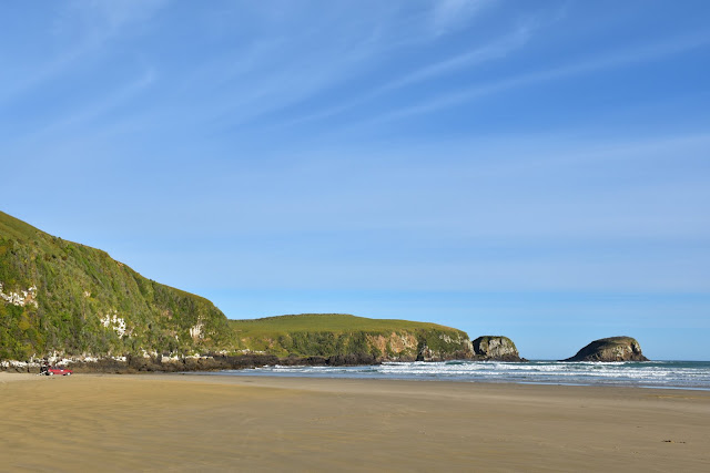 Beach, islands, windswept sky, spot of red against green